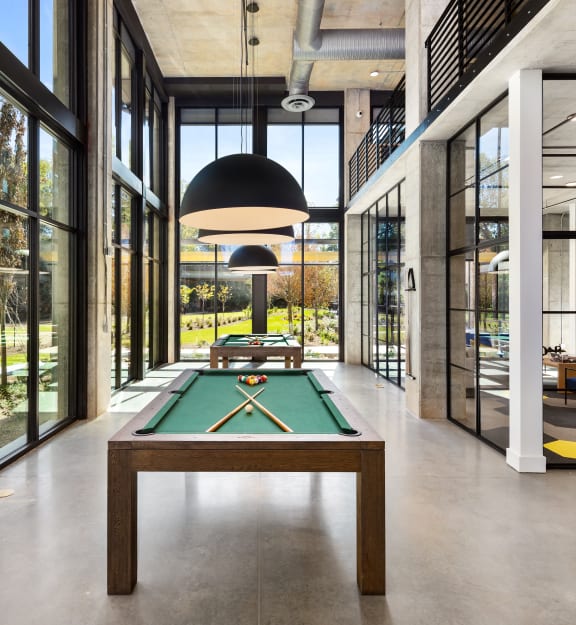 a pool table in the middle of a room with glass walls and a large window