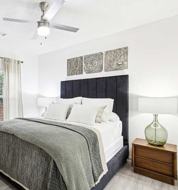 A bedroom with a bed, nightstand, and a ceiling fan.