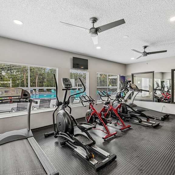 A gym with treadmills, exercise bikes, and a fan.