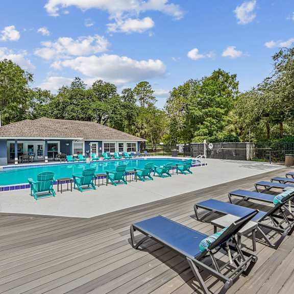 A poolside area with sun loungers and a building in the background.
