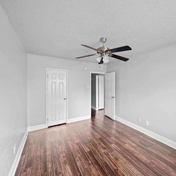 A room with a ceiling fan and wooden floors.