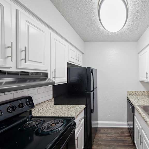 A kitchen with black appliances and white cabinets.