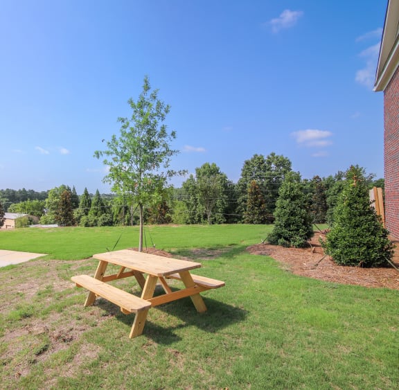 a picnic table with a swing in a grassy area