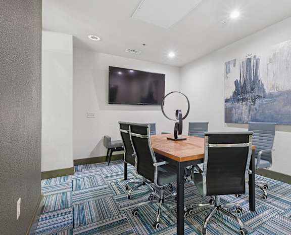 A conference room with a large painting on the wall and a television.