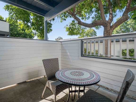 A patio with a table and chairs under a tree.