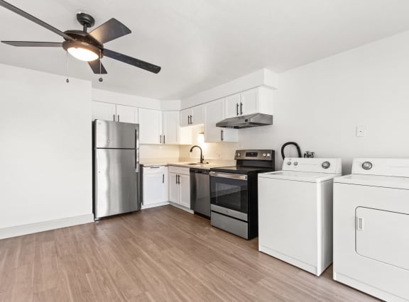 a white kitchen with stainless steel appliances and a ceiling fan