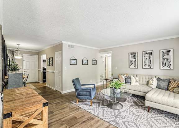 A living room with a couch, chairs, and pictures on the wall.