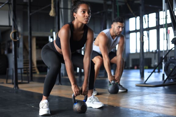 a man and woman lifting weights in a gym