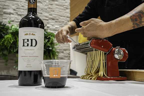 A bottle of Ed Emundo 2013 Cabernet Sauvignon is on a table next to a cup of wine and a pasta maker.