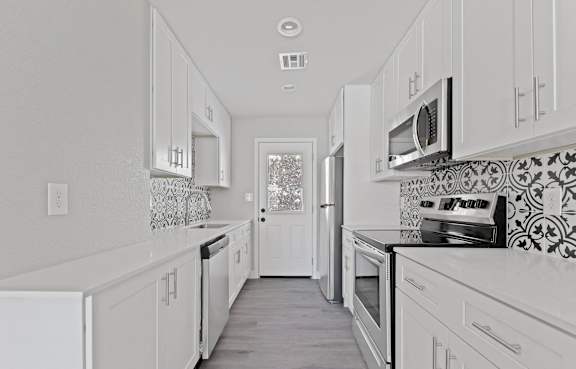 A white kitchen with a tile backsplash and a window.