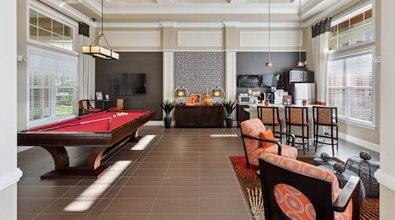 A room with a pool table and a bar area.