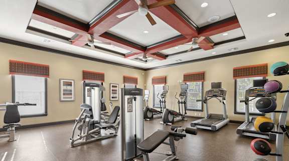 A gym with a variety of equipment including treadmills, weight machines, and free weights.