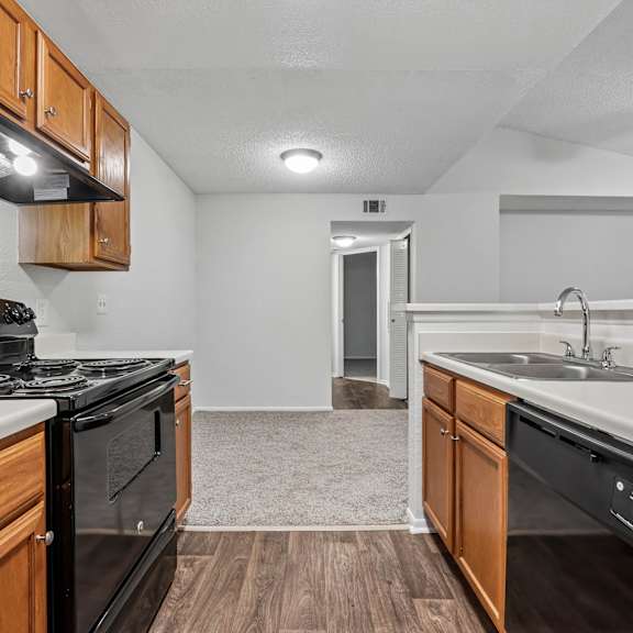 A kitchen with a black stove top oven and a black dishwasher.