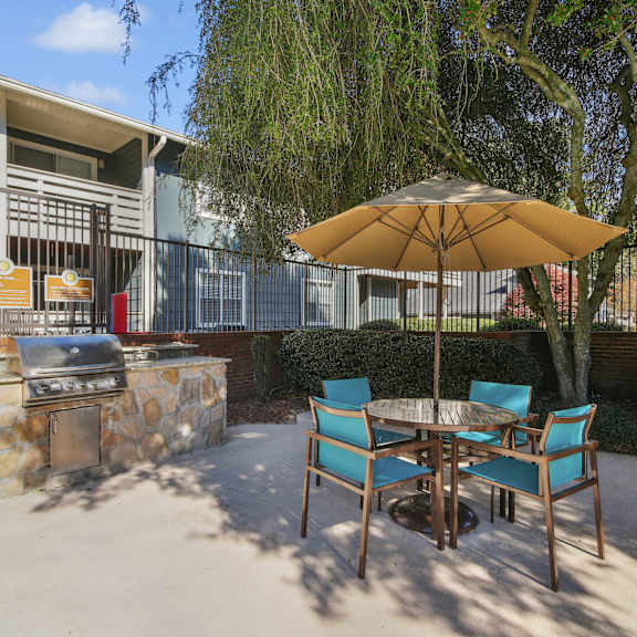 A patio with a table, chairs and an umbrella.