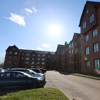 A sunny day at a parking lot in front of a red brick building.