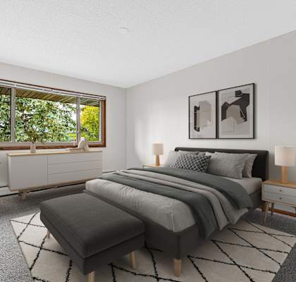 A bedroom with a large bed and a window overlooking a green tree.