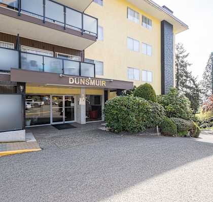 A yellow building with a glass entrance and a sign that says DUNSMUIR.