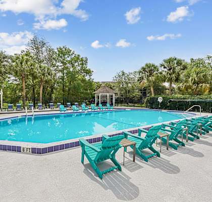 A pool with a gazebo and trees in the background.