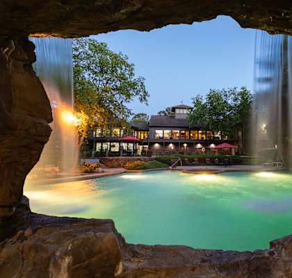 a pool with a waterfall and a building in the background