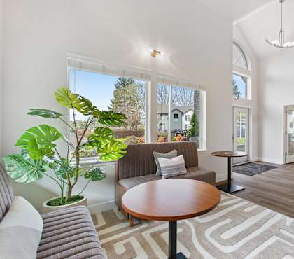 A living room with a grey couch, a brown table, and a rug with a geometric pattern.