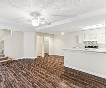 a renovated living room with a kitchen and a ceiling fan