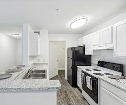 a kitchen with white cabinets and a black stove and refrigerator