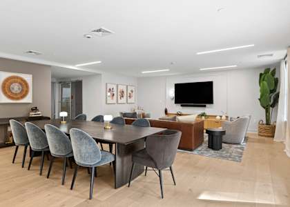 A modern dining room with a large table and grey chairs.