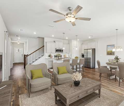 a living room with couches and chairs and a table and a ceiling fan