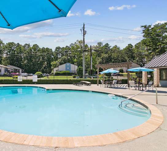 A round swimming pool with a blue umbrella above it.