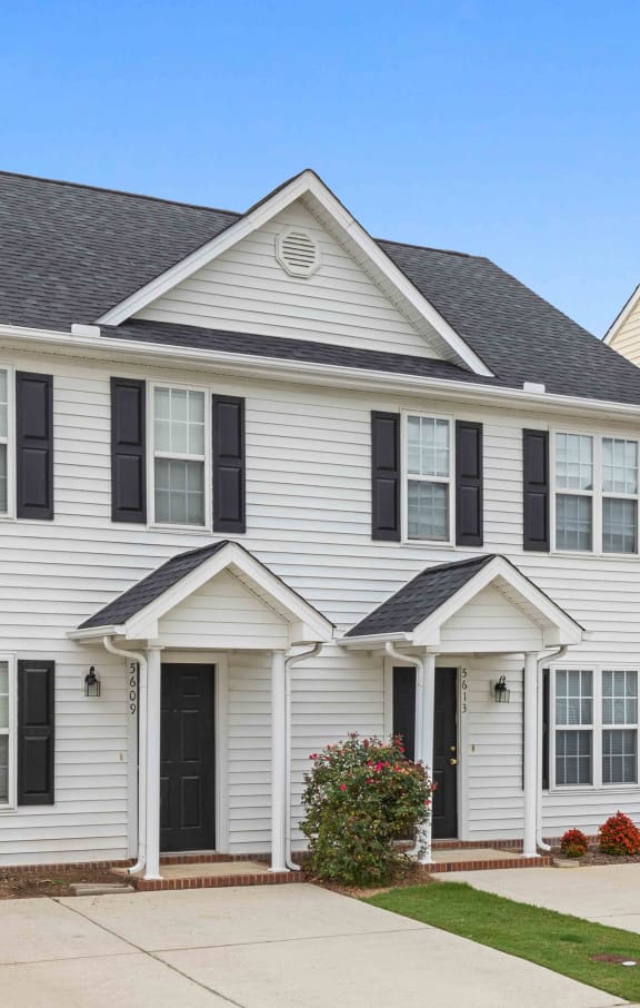 a white house with black shutters and a driveway