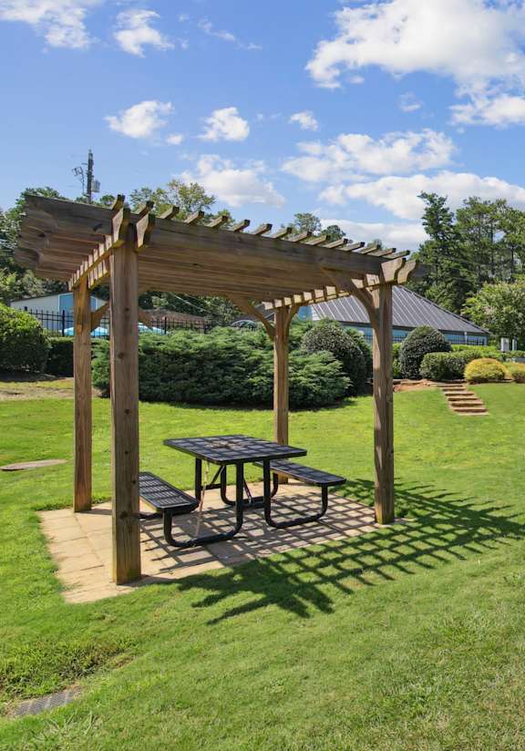 A sunny day at a park with picnic tables and pergolas.