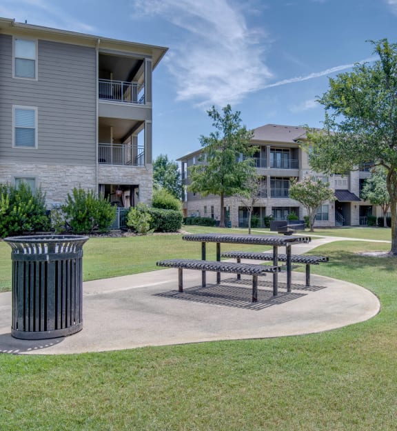 a picnic area with a trash can in front of an apartment building