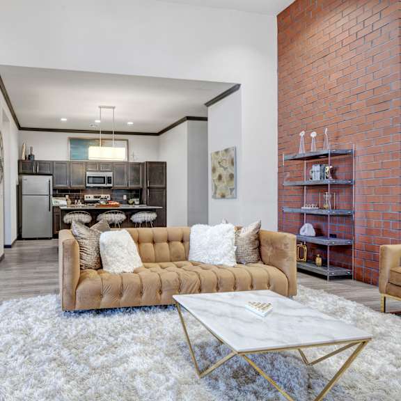 The lounge at 71 at Tulsa Hills with a couch, coffee table, plush chair, table and chairs, and kitchen. 