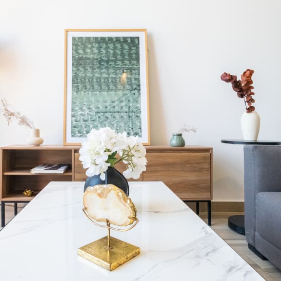 a living room with a white marble table and a blue vase with white flowers on it