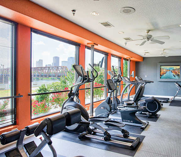 A gym with treadmills, exercise bikes and a view of the city.