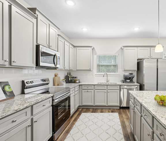 a large kitchen with white cabinets and marble counter tops