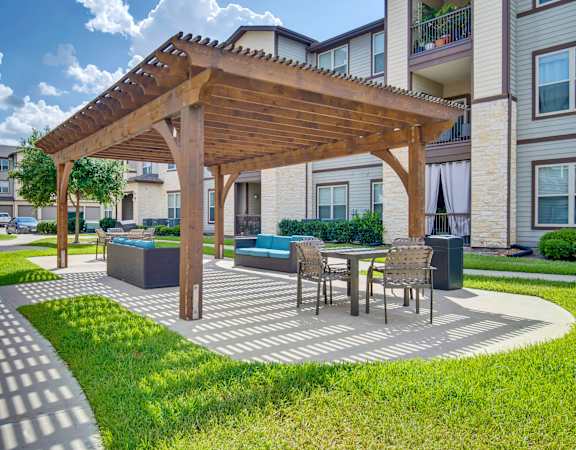 a patio with a table and chairs under a wooden pavilion