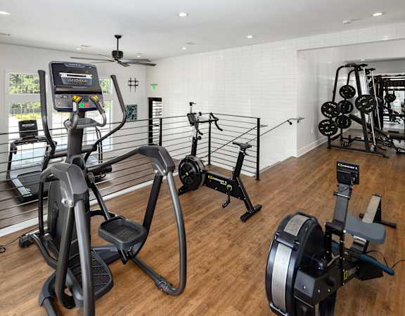 a gym with exercise equipment and weights on a wooden floor