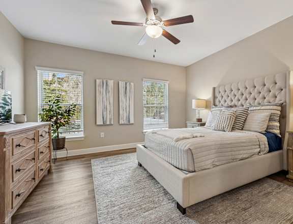 A bedroom with a large bed, a dresser, and a ceiling fan.