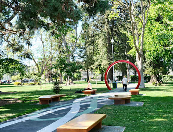 A park with a red sculpture and benches.