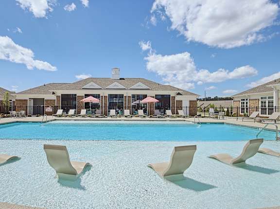A large swimming pool with lounge chairs and a building in the background.