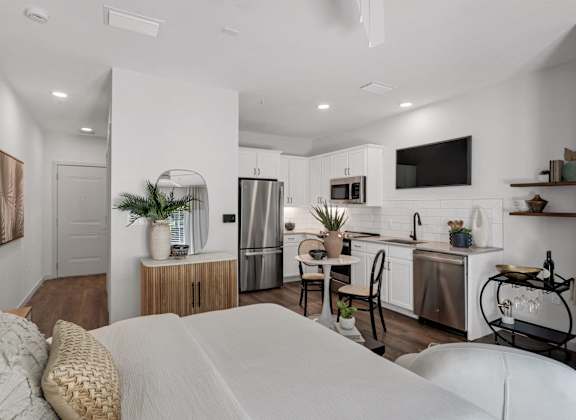 A modern kitchen with a refrigerator, sink, and a countertop with a microwave and a plant on it.
