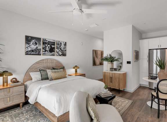 A bedroom with a large bed, a chair, and a ceiling fan.