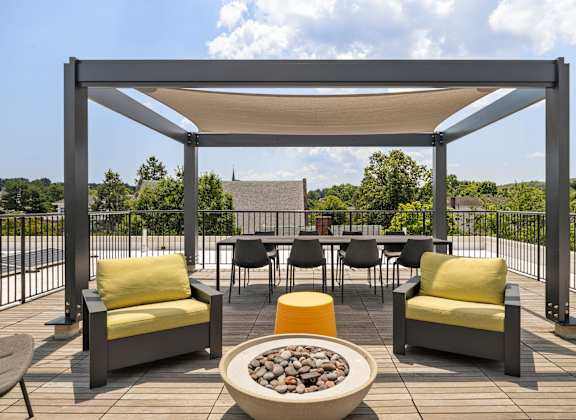 A patio with a fire pit and chairs.
