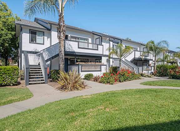 A modern apartment complex with a well-maintained lawn and landscaping.