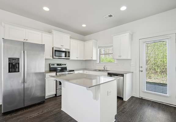 a white kitchen with stainless steel appliances and white cabinets