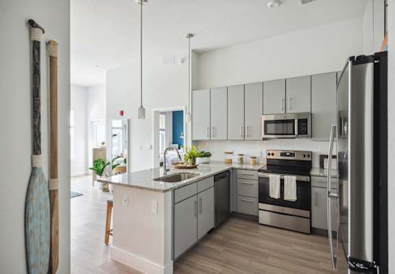 A modern kitchen with stainless steel appliances and wooden floors.