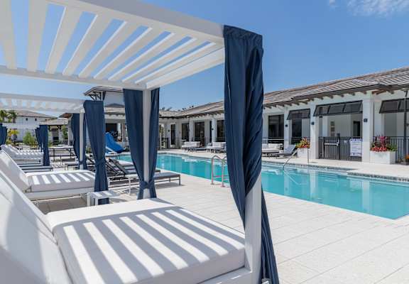 A poolside area with sun loungers and a white pergola.