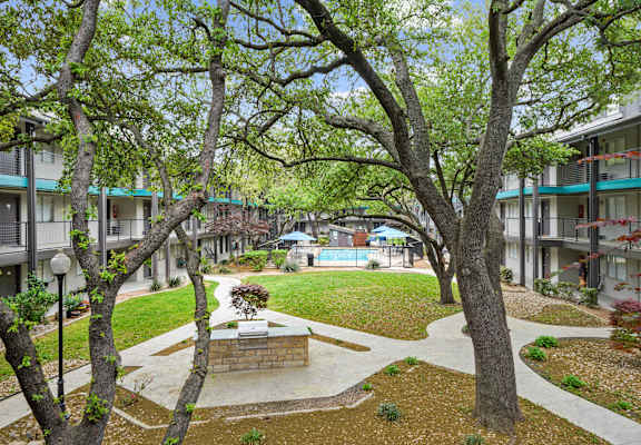A courtyard with a fountain surrounded by trees and buildings.