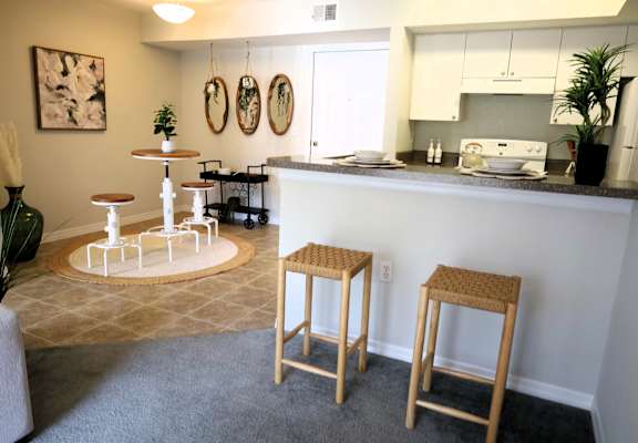 a kitchen and living room with a bar and stools